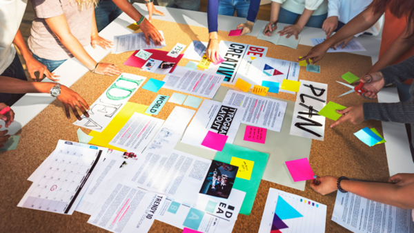 Mehrere Personen arbeiten gemeinsam an einer Plakatwand