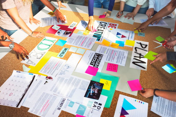 Mehrere Personen arbeiten gemeinsam an einer Plakatwand