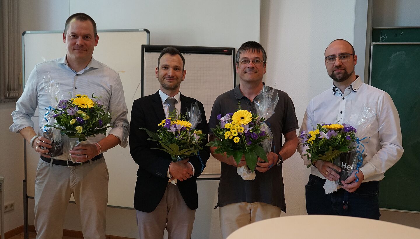 vier Personen mit Blumenstrauß