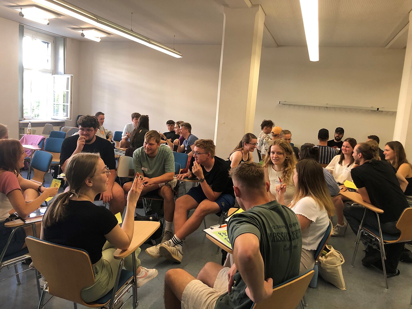 Ersti-Coaches werden auf ihre Arbeit vorbereitet und während ihres Einsatzes begleitet. (Foto: Peer-Zentrum) viele junge Menschen in einem Seminarraum diskutieren miteinander